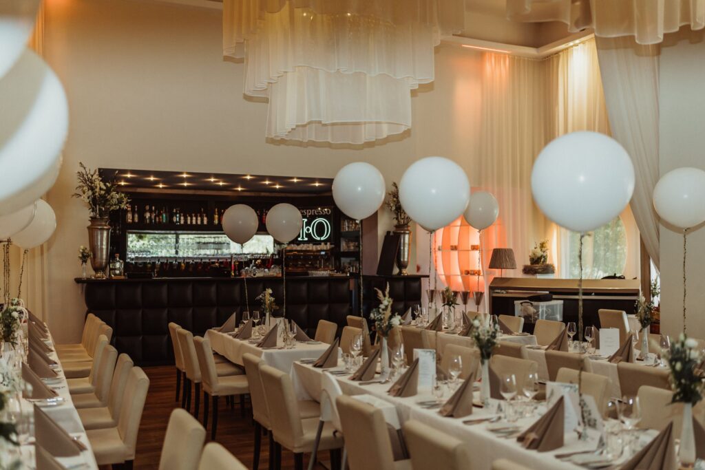 Pięknie udekorowane miejsce w restauracji z białymi balonami, idealnie nakrytymi stołami i przytulną atmosferą