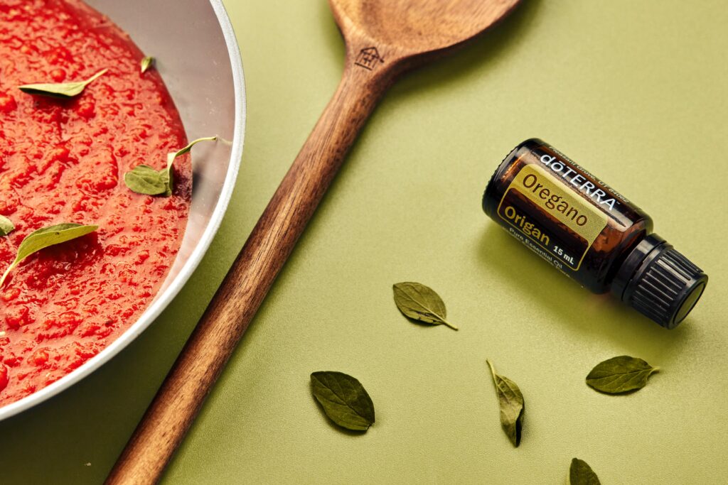 A close-up of delicious tomato soup paired with oregano oil and wooden spoon.